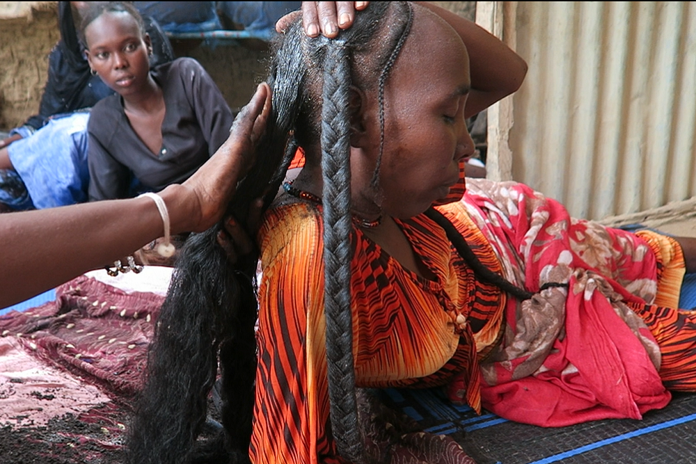 Woman applying chebe powder hair treatment to help reduce breakage