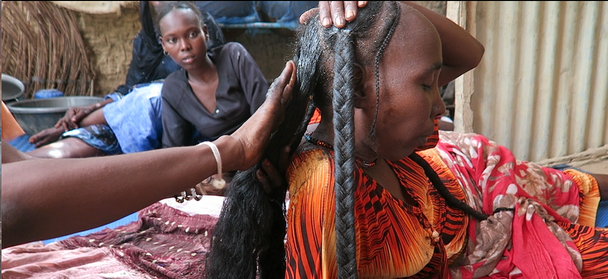 Woman applying chebe powder hair treatment to reduce breakage and support moisture